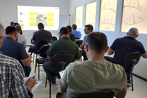 Alunos em aula teórica na Komatsu School, acompanhando apresentação em sala equipada